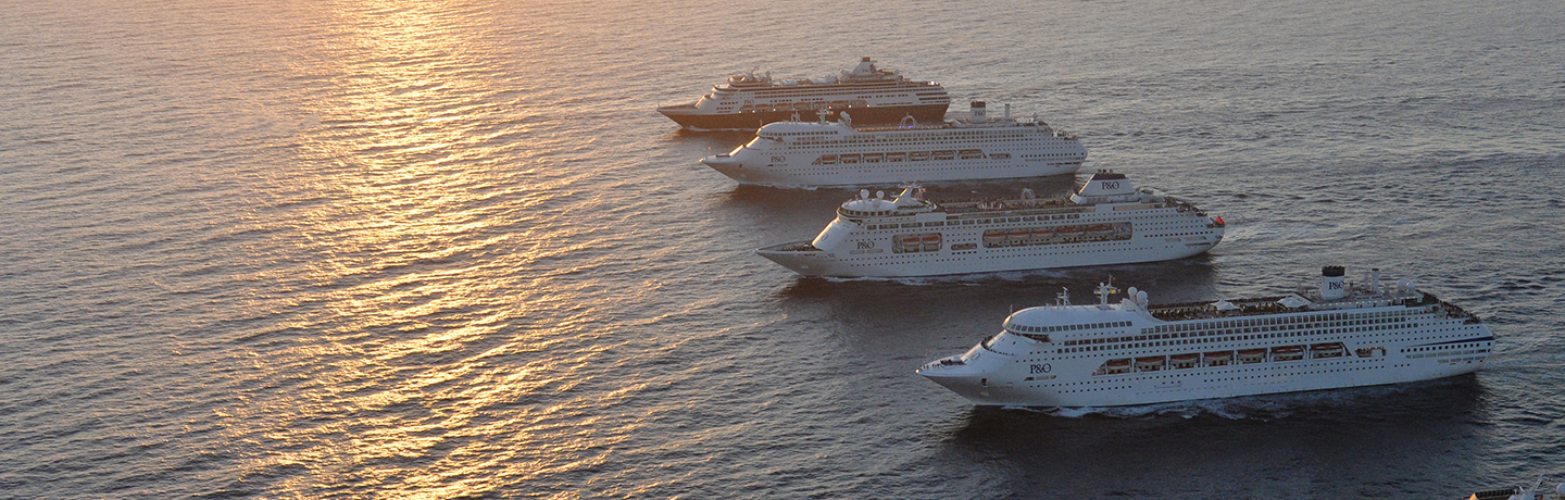 Four cruise ships in a row out at sea with the sun setting