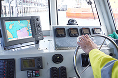 Hands piloting a vessel and following satellite navigation